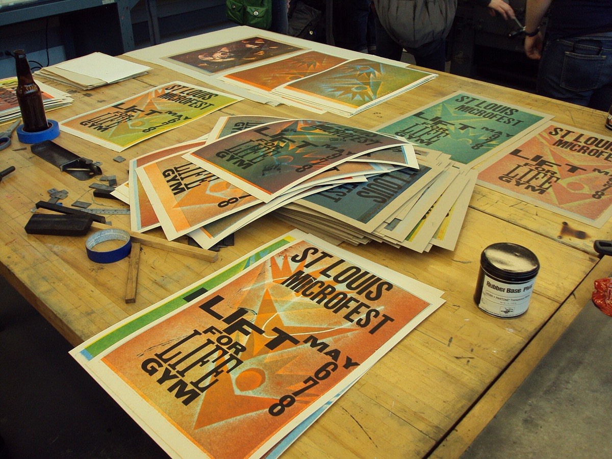 Freshly printed two-colour posters stacked and drying on a wooden work table